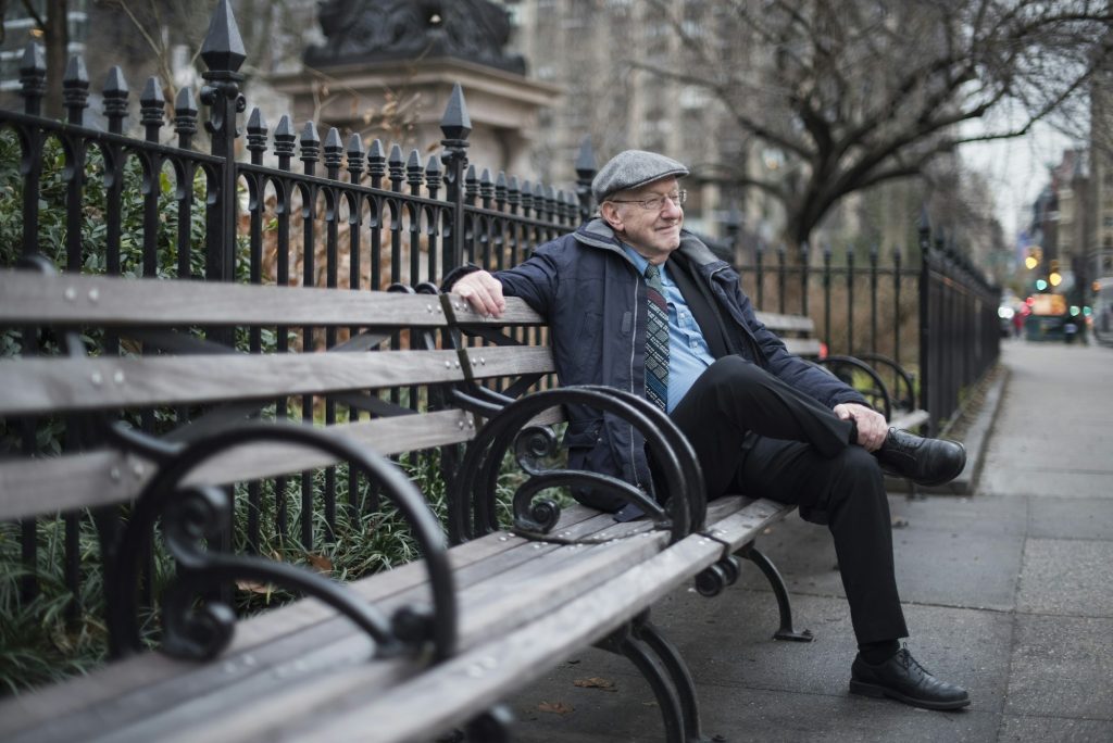 Man sitting on park bench smiling, Manhattan, New York, USA