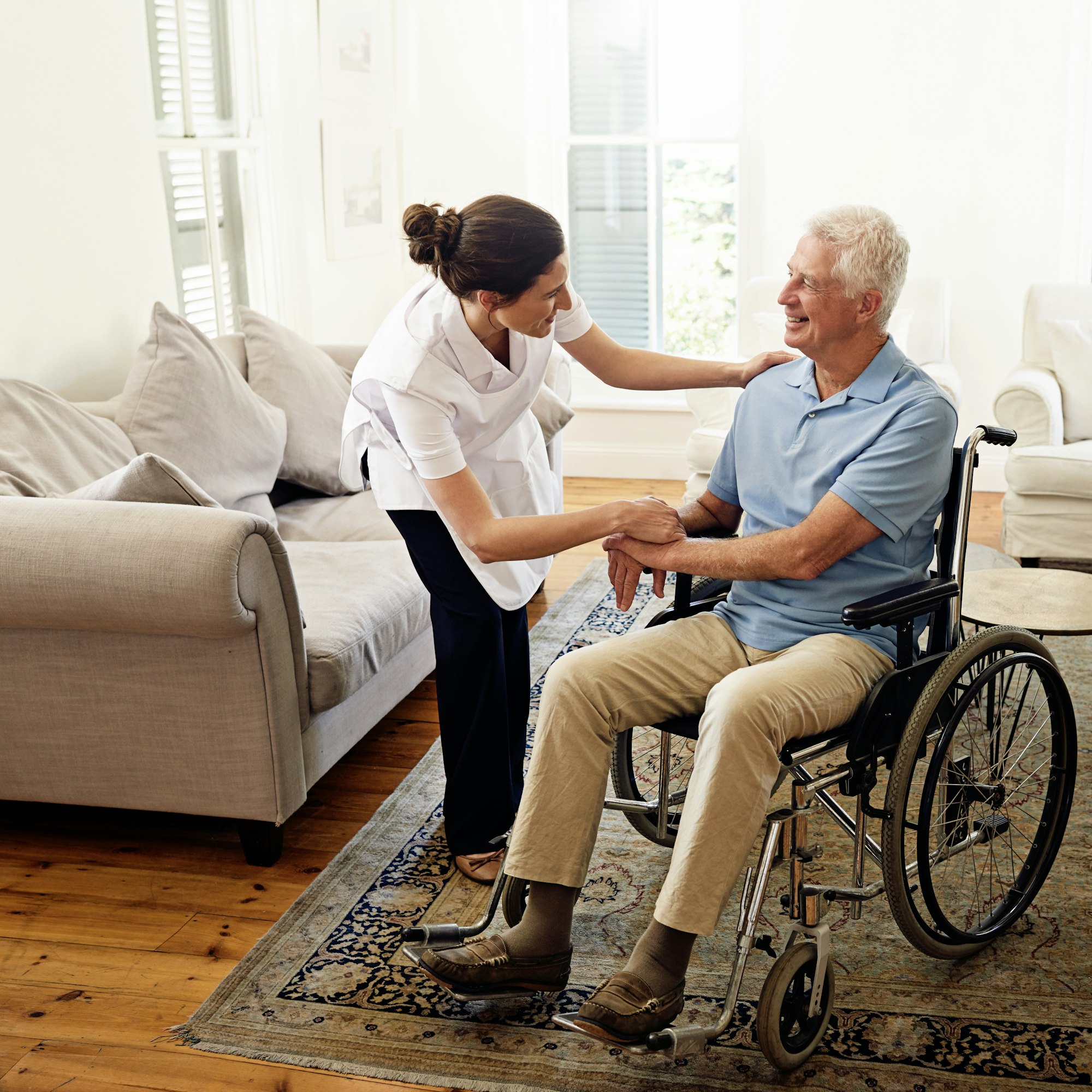 Shot of a caregiver helping a senior man in a wheelchair at home